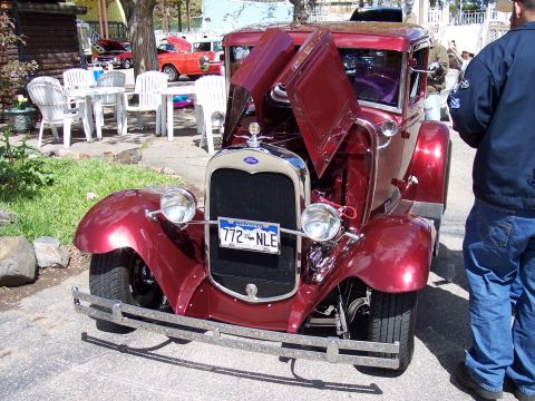 1972 Ford Ranchero - This maroon Ford Model A coupe has its hood open, revealing the engine bay. A red truck is parked behind it.
