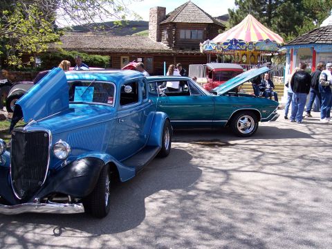 1972 Ford Ranchero - Two classic cars are on display at an outdoor event with people milling around.