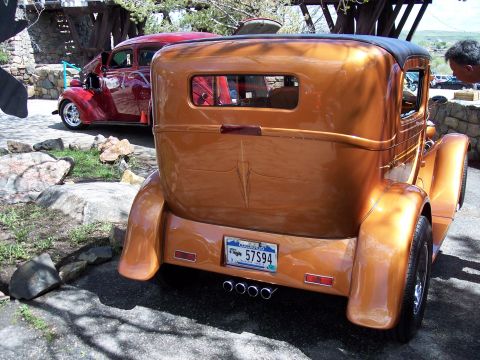 1972 Ford Ranchero - A copper-colored custom coupe with a pinstripe detail on the trunk is parked next to a red sedan.