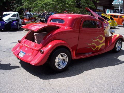 1972 Ford Ranchero - A red hot rod coupe with flame decals is parked on asphalt, with its trunk open.