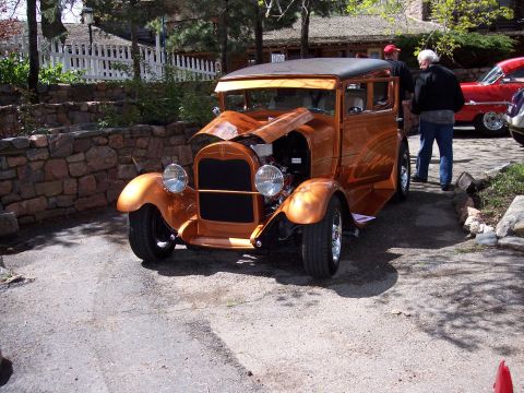 1972 Ford Ranchero - A custom hot rod sedan with a copper finish and exposed engine sits parked on a gravel driveway.