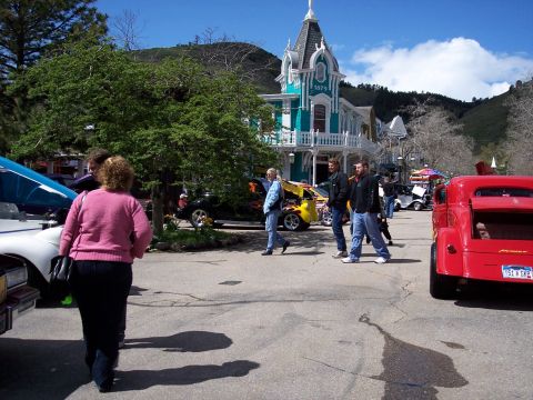 1972 Ford Ranchero - A red pickup truck is parked on a street with people walking by and a historic building in the background.
