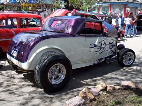 1972 Ford Ranchero - This custom hot rod features a two-tone paint scheme with purple flames and prominent rear tires, seen at an outdoor event.
