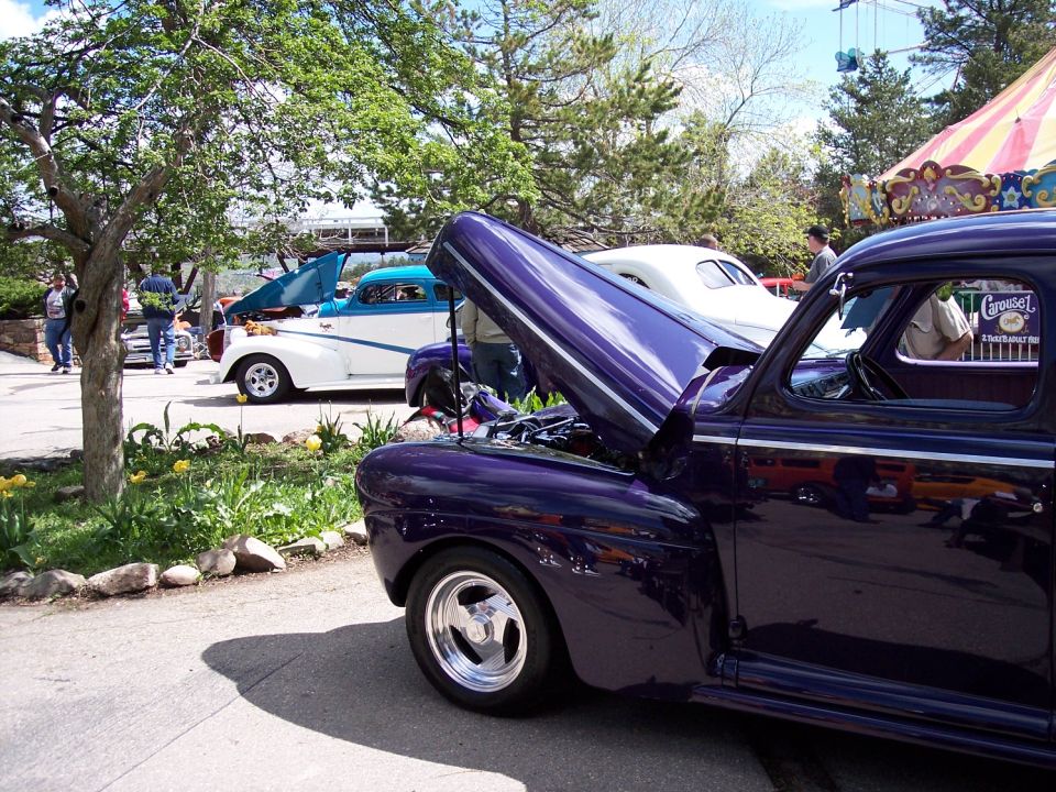Purple classic car with hood open, chrome wheels, parked outdoors