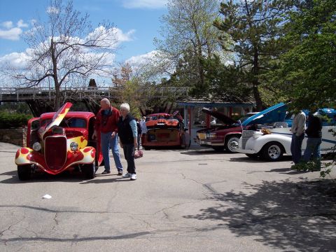 1972 Ford Ranchero - A red and yellow hot rod with flames is parked at an outdoor event, with people looking at it.