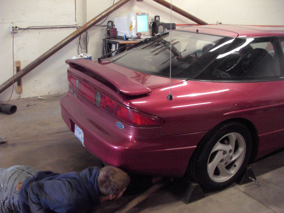 guy working under a red coupe, possibly a 1990s model