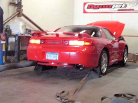 1989 Ford Probe - A red sports car is positioned on a dynamometer, with its hood open and exhaust pipe visible.