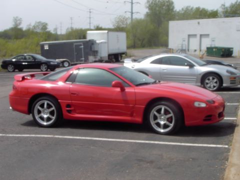 1989 Ford Probe - A red sports car is parked in a lot next to a silver coupe, with a trailer and truck in the background.