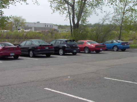 1989 Ford Probe - A row of vehicles are parked in an outdoor lot under a cloudy sky.
