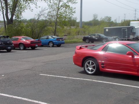 1989 Ford Probe - Several cars are parked in an outdoor lot, including a red sports car in the foreground.