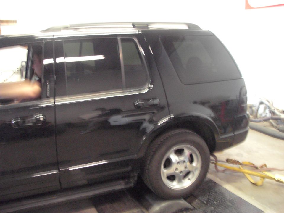 Side view of a black SUV on a dynamometer. The SUV appears to be a Ford Explorer from the early 2000s