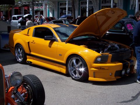 1972 Ford Ranchero - A bright yellow Ford Mustang GT is parked with its hood up, showing off the engine bay.