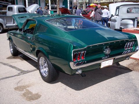 1972 Ford Ranchero - A green fastback coupe is parked on pavement, with other vehicles and people in the background.