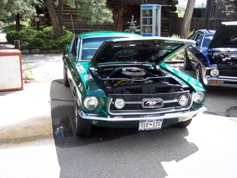 1972 Ford Ranchero - A green 1967 Ford Mustang is parked with its hood open, next to another vehicle.