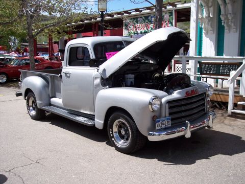 1972 Ford Ranchero - A silver GMC pickup truck is parked outdoors with its hood open, showing the engine compartment.