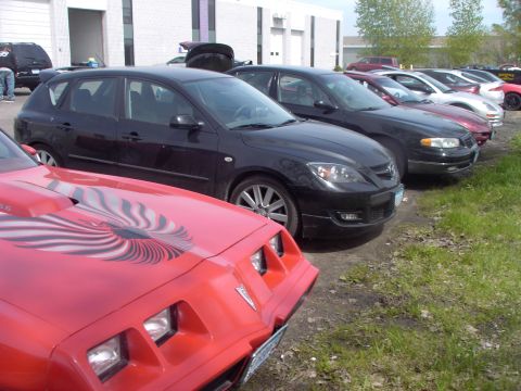 1989 Ford Probe - Several cars are parked in a lot outside a building, with a red car in the foreground.