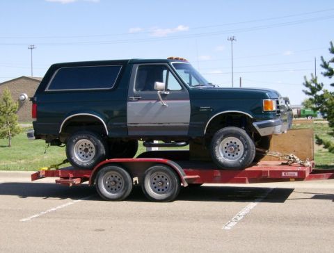 2000 Ford F-250 - A dark green 1992 Ford Bronco is transported on a red trailer.