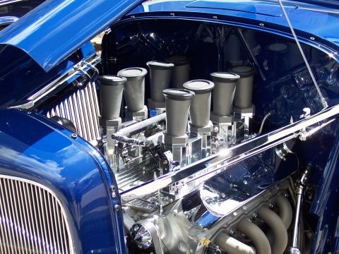 1972 Ford Ranchero - The polished engine bay of a custom car features a V8 engine with eight individual carburetors and chrome accents.
