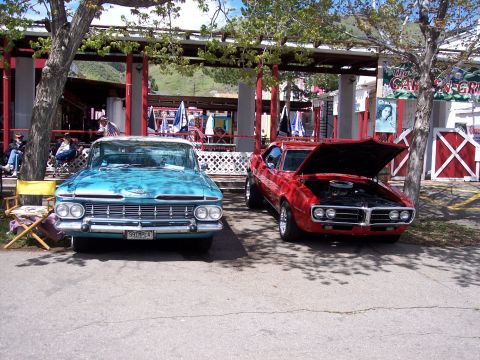 1972 Ford Ranchero - Two vintage cars are parked side-by-side in front of a building with outdoor seating.