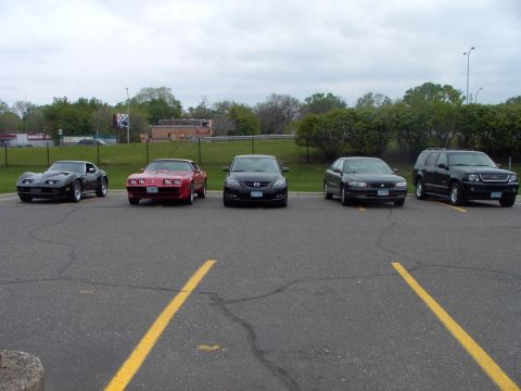 1989 Ford Probe - A red 1989 Pontiac Firebird is parked in a lot alongside four other vehicles.
