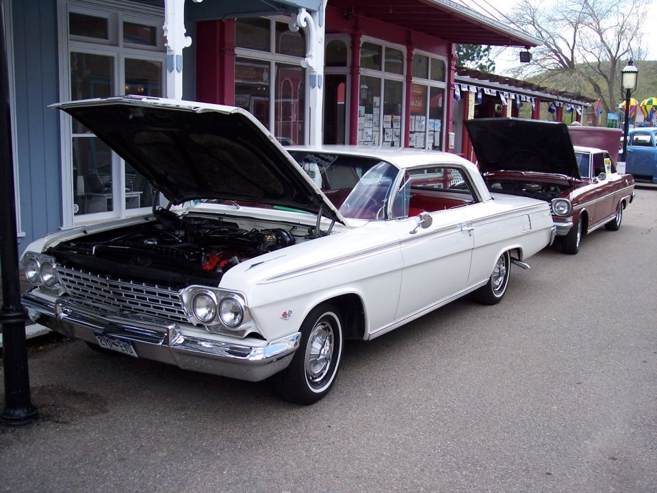 White 1962 Chevrolet Impala coupe with hood open, parked on asphalt