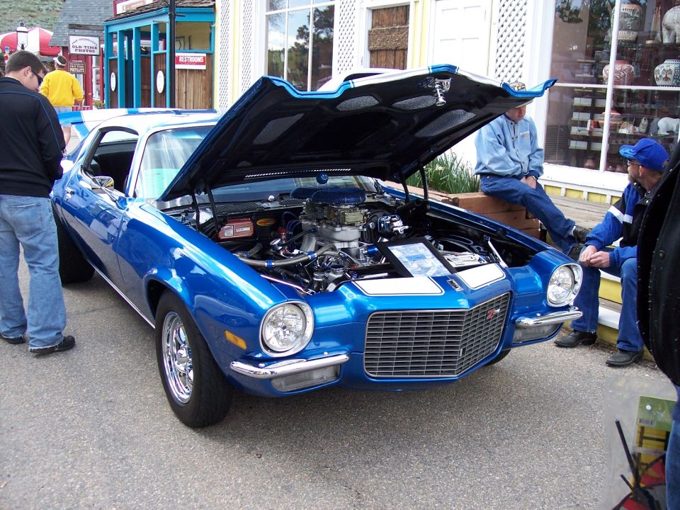 Blue muscle car, front view, hood open, chrome wheels, white racing stripes on hood and roof