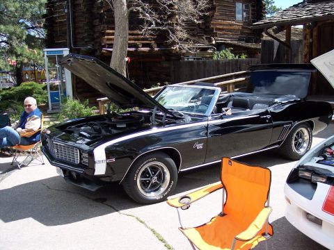 1972 Ford Ranchero - A black 1969 Chevrolet Camaro SS convertible is displayed with its hood open, parked next to another vehicle.