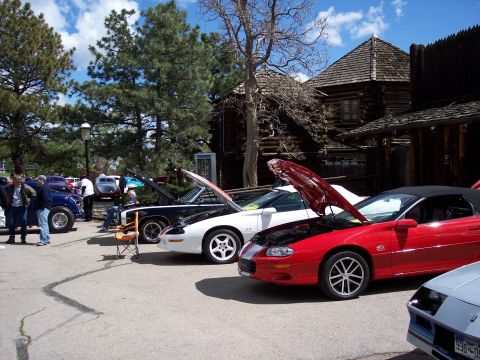 1972 Ford Ranchero - Cars are displayed with their hoods open at an outdoor gathering, with rustic wooden structures in the background.