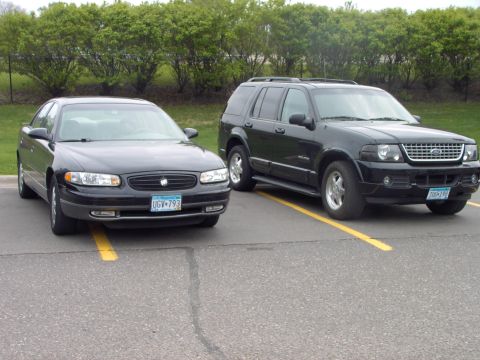 1989 Ford Probe - Two black vehicles, a Ford Explorer and a Buick Regal, are parked in adjacent spots.
