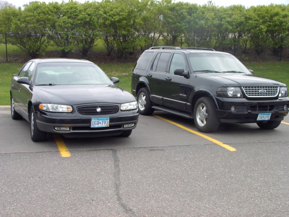 Black Ford Explorer and a black Buick Regal parked side-by-side in parking spots