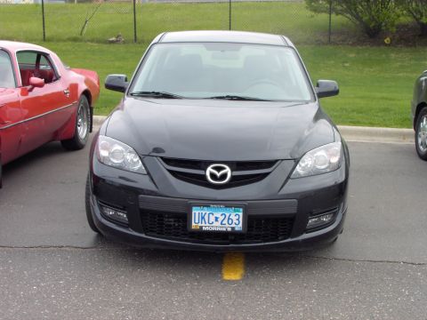 1989 Ford Probe - A black Mazda 3 is parked in front of a red car.