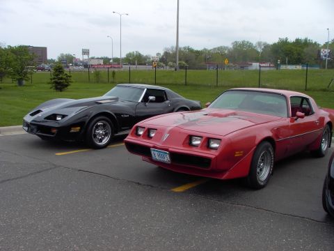 1989 Ford Probe - A red Pontiac Firebird and a black Chevrolet Corvette are parked next to each other in a parking lot.