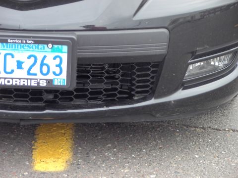 1989 Ford Probe - Close-up of a vehicle's front grille and license plate, with a yellow line on the pavement.