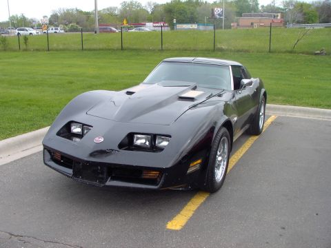1989 Ford Probe - This black Chevrolet Corvette is parked in a lot, showing off its distinctive hood scoops.