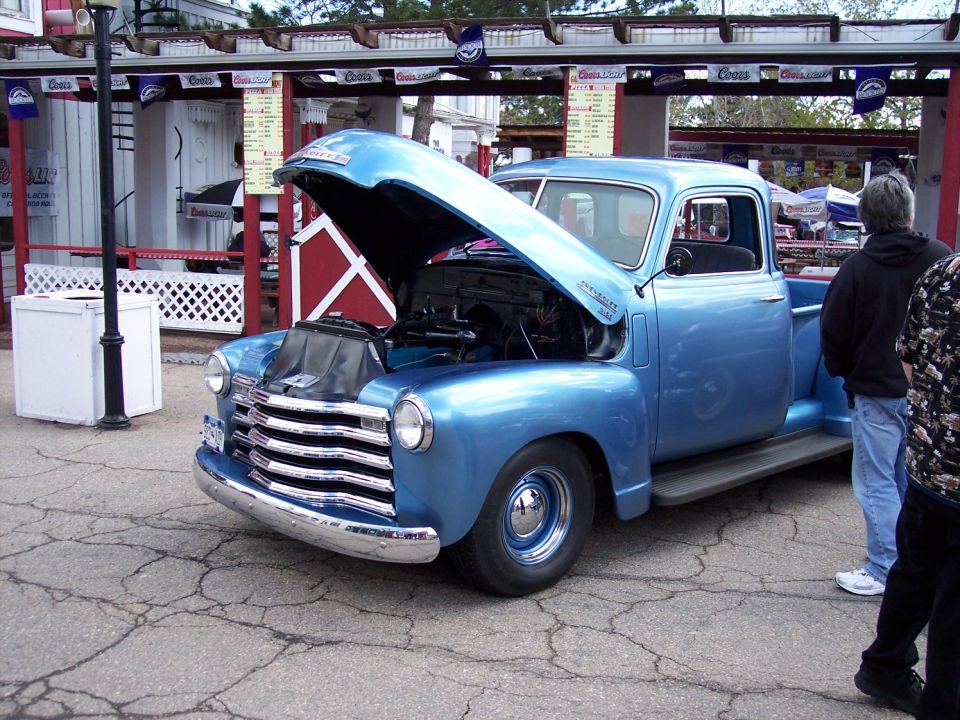 Blue Chevrolet pickup truck, hood open, showing engine. Parked outdoors