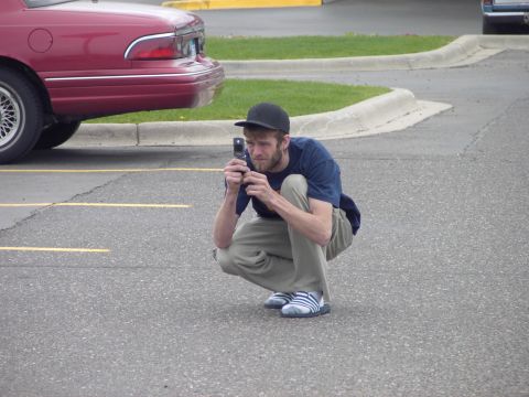 1989 Ford Probe - A man crouches to photograph the rear of a red 1992 Mercury Grand Marquis.