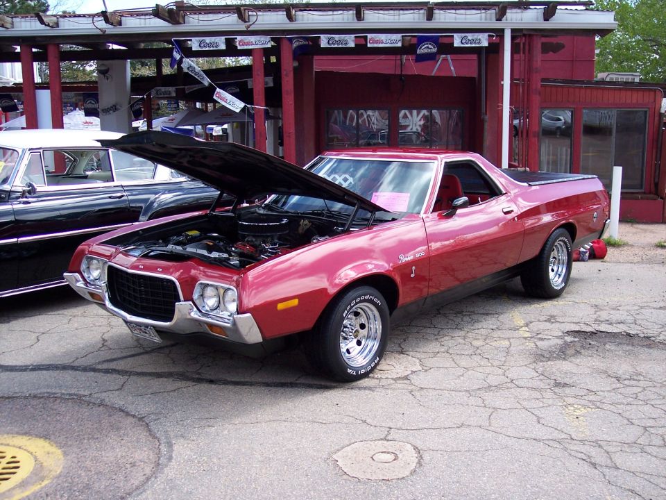Red 1972 Ford Ranchero with hood open, parked next to a black car