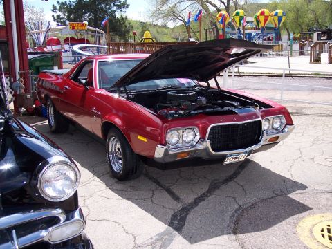 1972 Ford Ranchero - A red 1972 Ford Ranchero is parked with its hood open, revealing the engine, next to another vehicle.