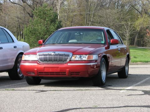 2003 Ford Crown Victoria - A red Mercury Grand Marquis is parked in a lot next to another vehicle.