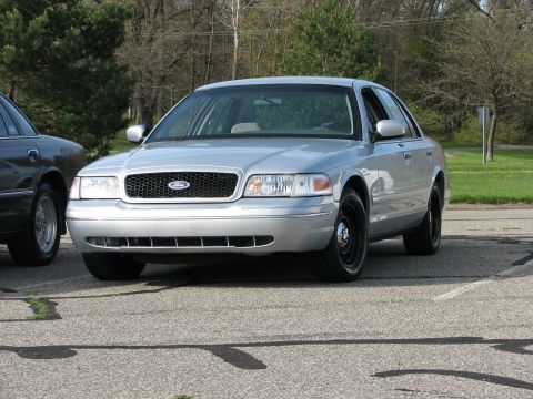 2003 Ford Crown Victoria - A silver 2003 Ford Crown Victoria is shown from the front, with another vehicle partially visible to its left.