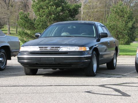 2003 Ford Crown Victoria - Front view of a black sedan, likely a 1995 Ford Crown Victoria, parked next to another vehicle.
