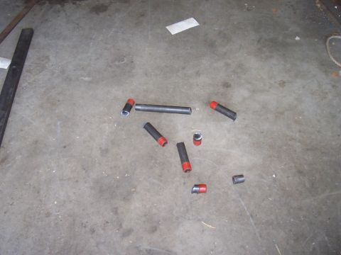 1994 Ford F-150 - Metal tubes and caps on a concrete floor, possibly parts for a project.