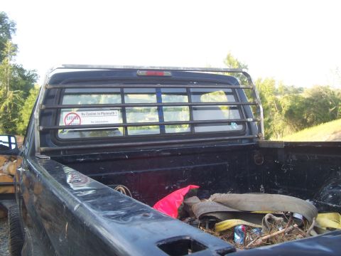 1994 Ford F-150 - The rear of a pickup truck is shown, with a metal rack behind the cab and various items in the bed.