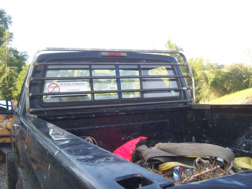 Pickup truck bed with a metal rack on the back window. Stuff is piled in the bed