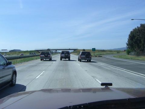 1980 Ford F-250 - Multiple SUVs travel down the highway on a sunny day.