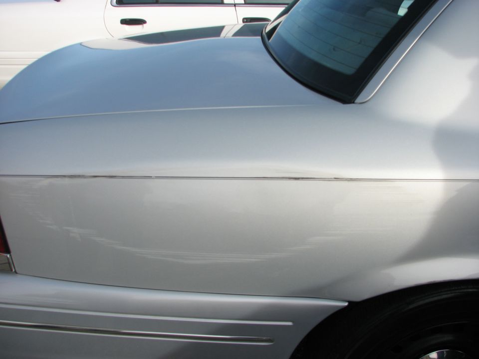 Silver 2003 Ford Crown Victoria rear quarter panel and trunk lid, showing a chrome trim line and minor scuffs