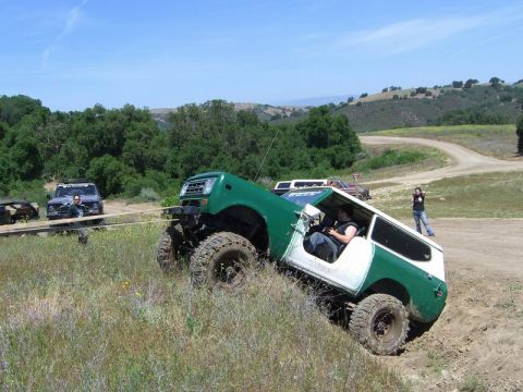 1980 Ford F-250 - An off-road vehicle with a two-tone paint scheme navigates a challenging terrain, assisted by a tow rope from another vehicle.