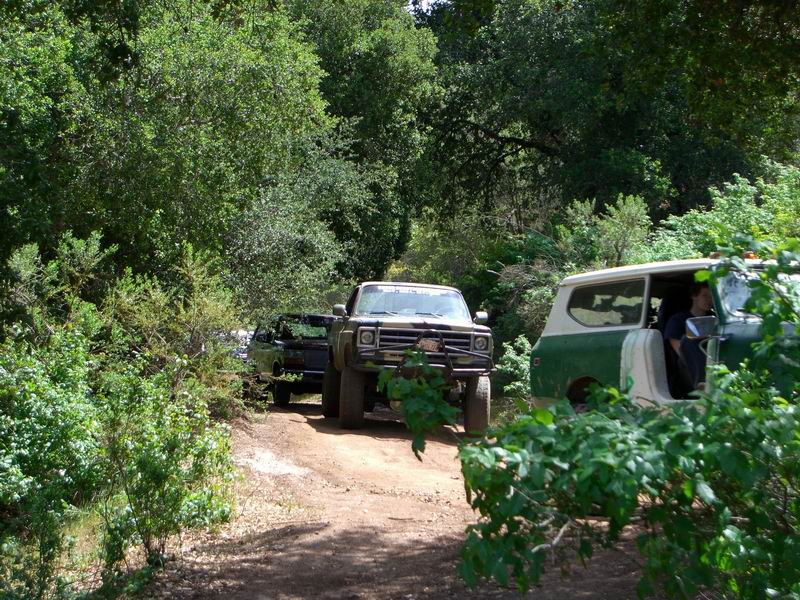 Front view of a lifted 1973-1979 Ford F-Series truck with a brush guard, followed by another truck and an International Scout II