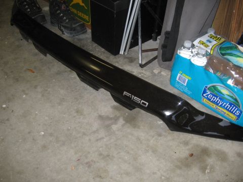 1974 Ford F-100 - Black F-150 bug shield part shown on garage floor with other items.