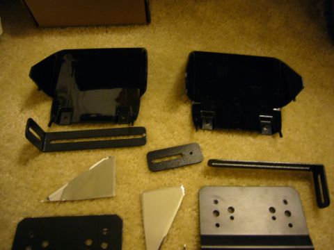 2000 Ford Crown Victoria - Various black metal brackets and plates are laid out on a carpeted surface.